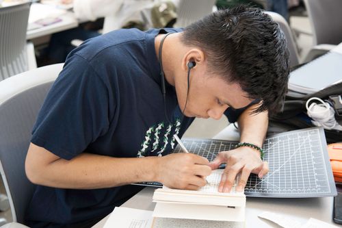 Free A student intensely focused on cutting and tracing as part of an art project, representing creativity and education. Stock Photo