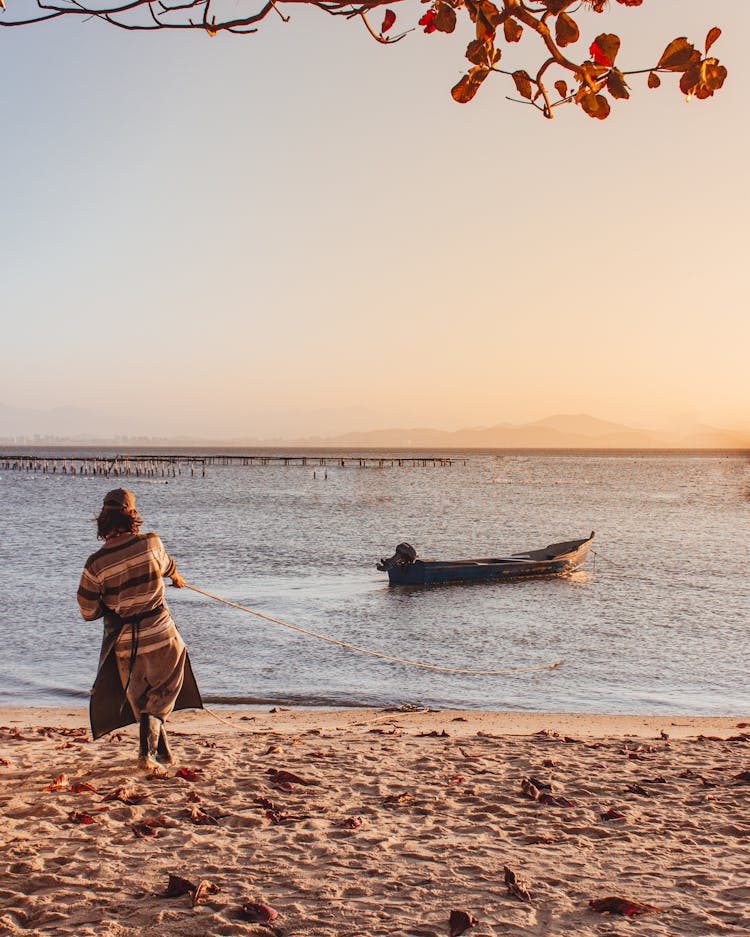 Man In Striped Shirt Pulling A Rope By The Seashore