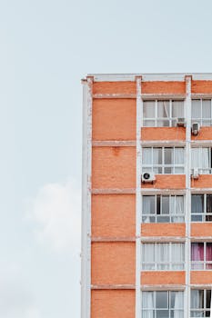 A minimalist close-up of a modern brick apartment building against a bright blue sky.