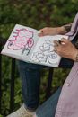 High angle of crop anonymous left handed artist drawing in sketchbook in park