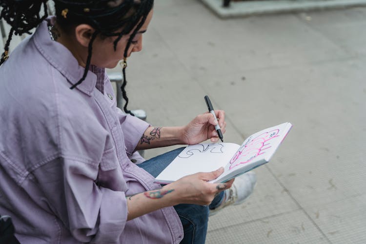 Female Artist Sitting On Street And Doing Sketches