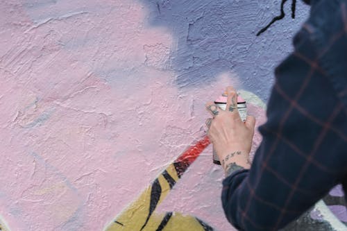Photo of a Person Spraying Pink Paint on a Wall