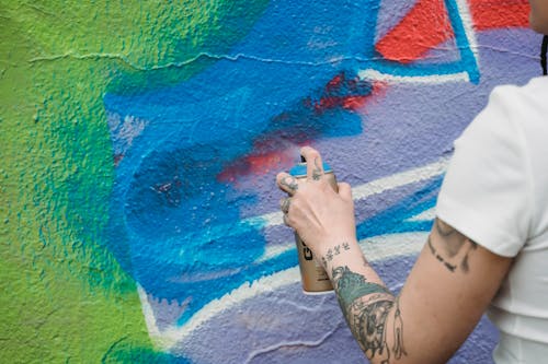 Close-Up Photo of a Person Holding a Blue Spray Paint Can