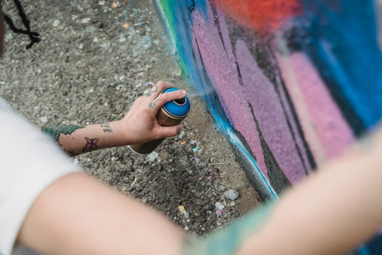 High-Angle Shot Of A Person's Hand Spraying Paint On A Wall