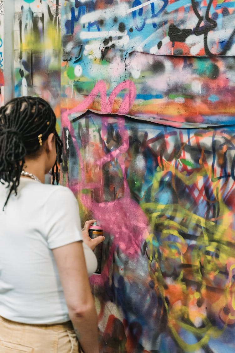 A Woman In White T-shirt Spraying Paint On Wall