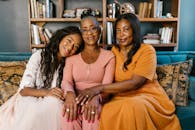 三个美丽的黑人女性一起坐在沙发上，在室内微笑