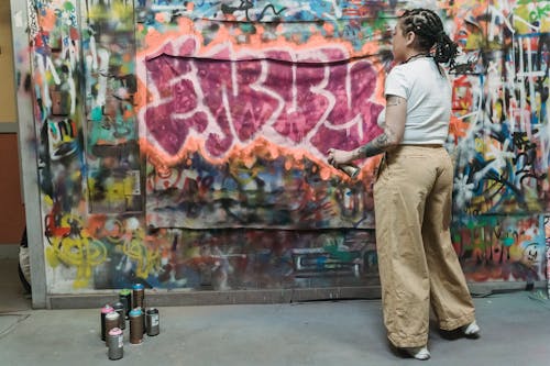 Back View of a Woman Spraying Paint on a Wall