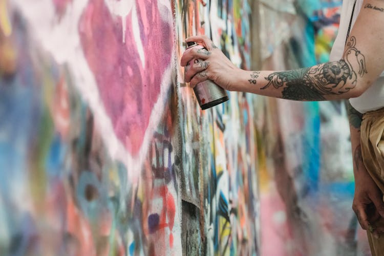 A Person Spraying Aerosol Paint To A Wall 