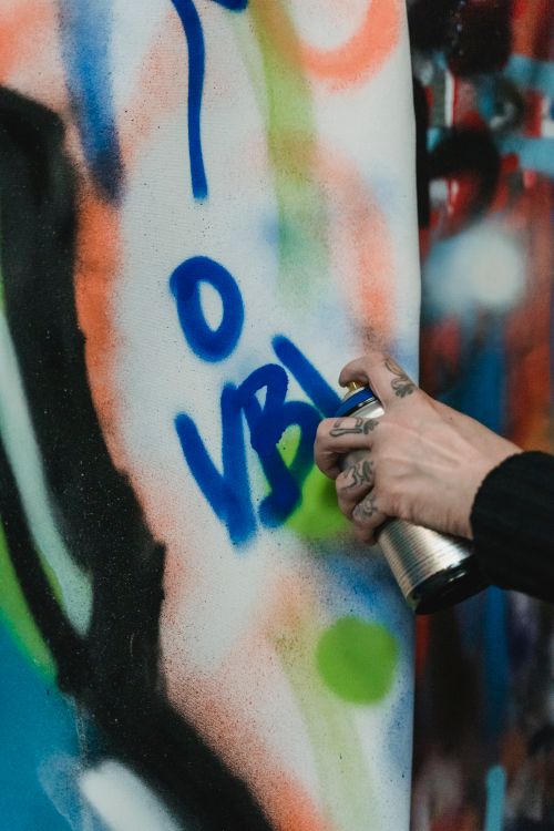 Free Close-up of a hand spray painting vibrant graffiti art on a wall. Stock Photo