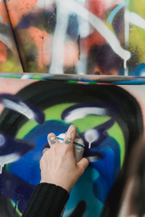 Free Close-up of a hand spray painting colorful graffiti art on a wall. Stock Photo