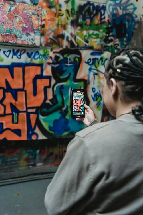 Photo of a Woman Taking Photo of a Wall with Graffiti