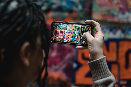 A Person Using Her Phone to Take a Picture of a Wall with Graffiti