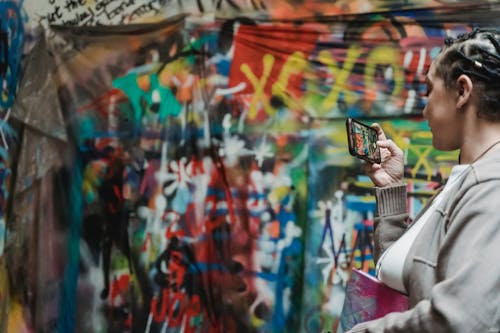 Woman Taking Picture of a Wall with a Street Art