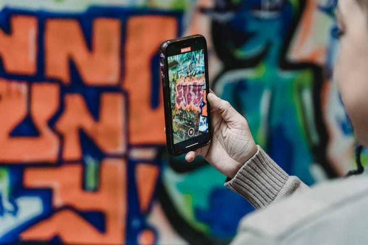 Person Taking Photo Of Graffiti On Cellphone