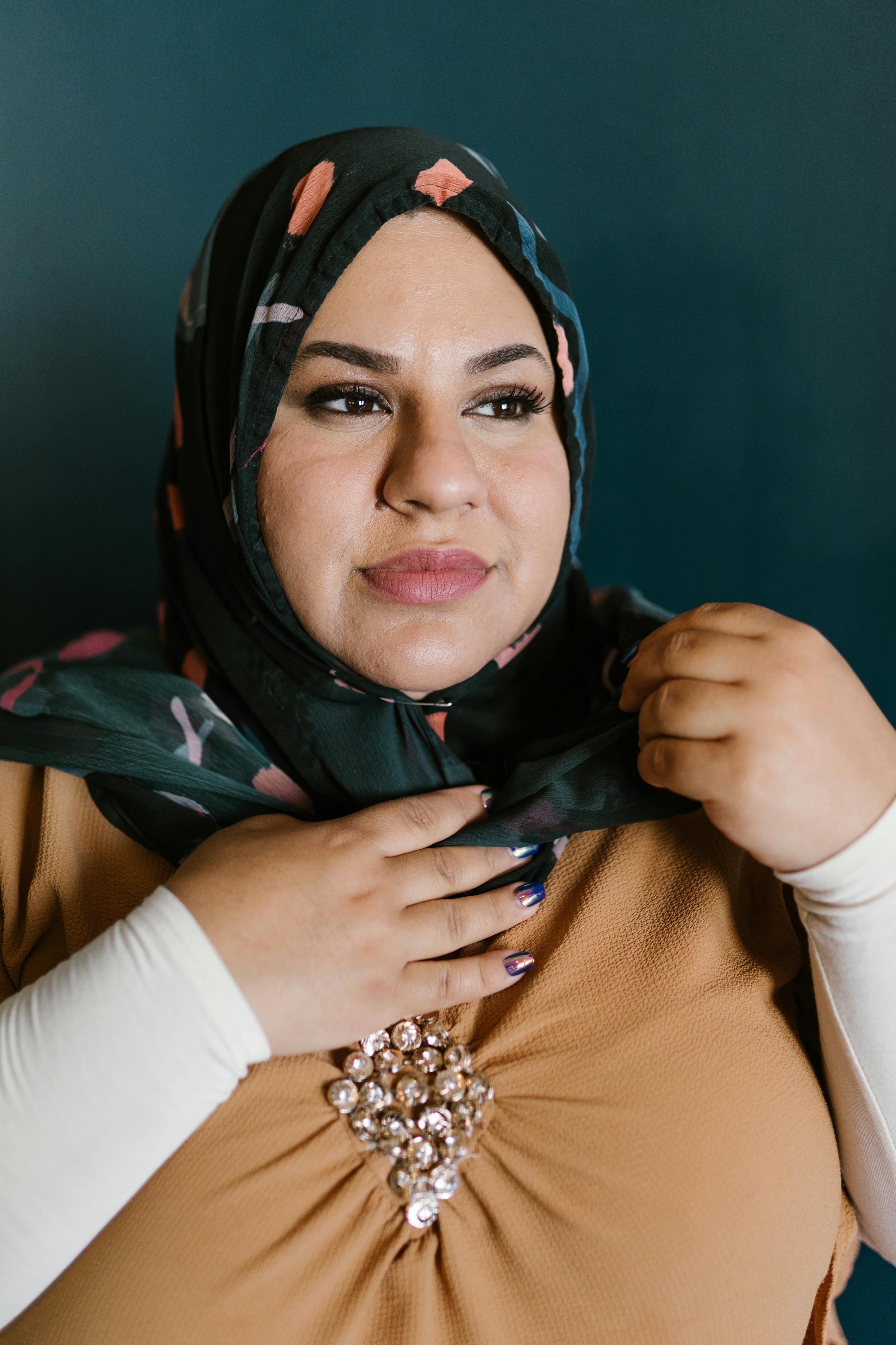 Close-up portrait of a woman wearing a colorful hijab with intricate embroidery, exuding confidence.