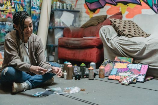 Young woman artist in studio surrounded by graffiti artwork and paint cans.