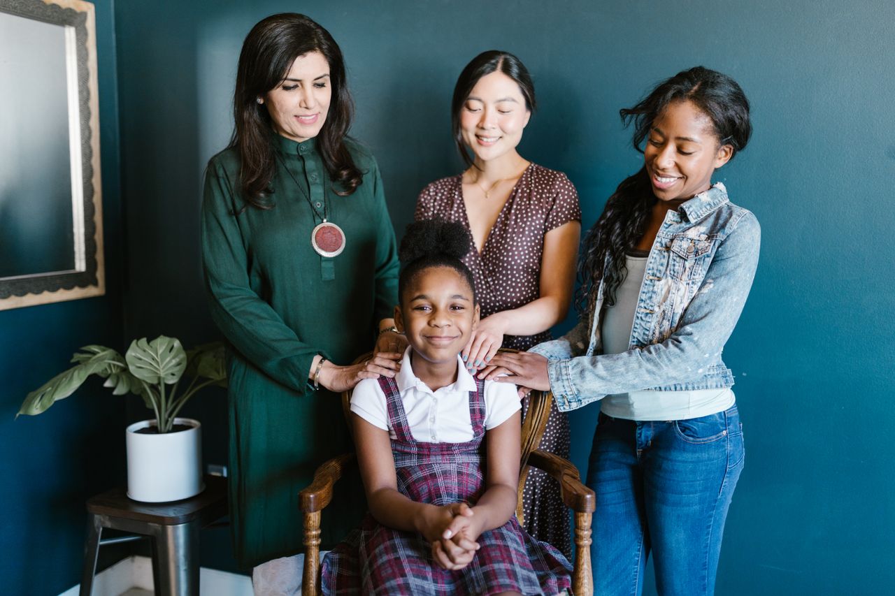 multiracial group of women and a girl smiling together indoors showcas