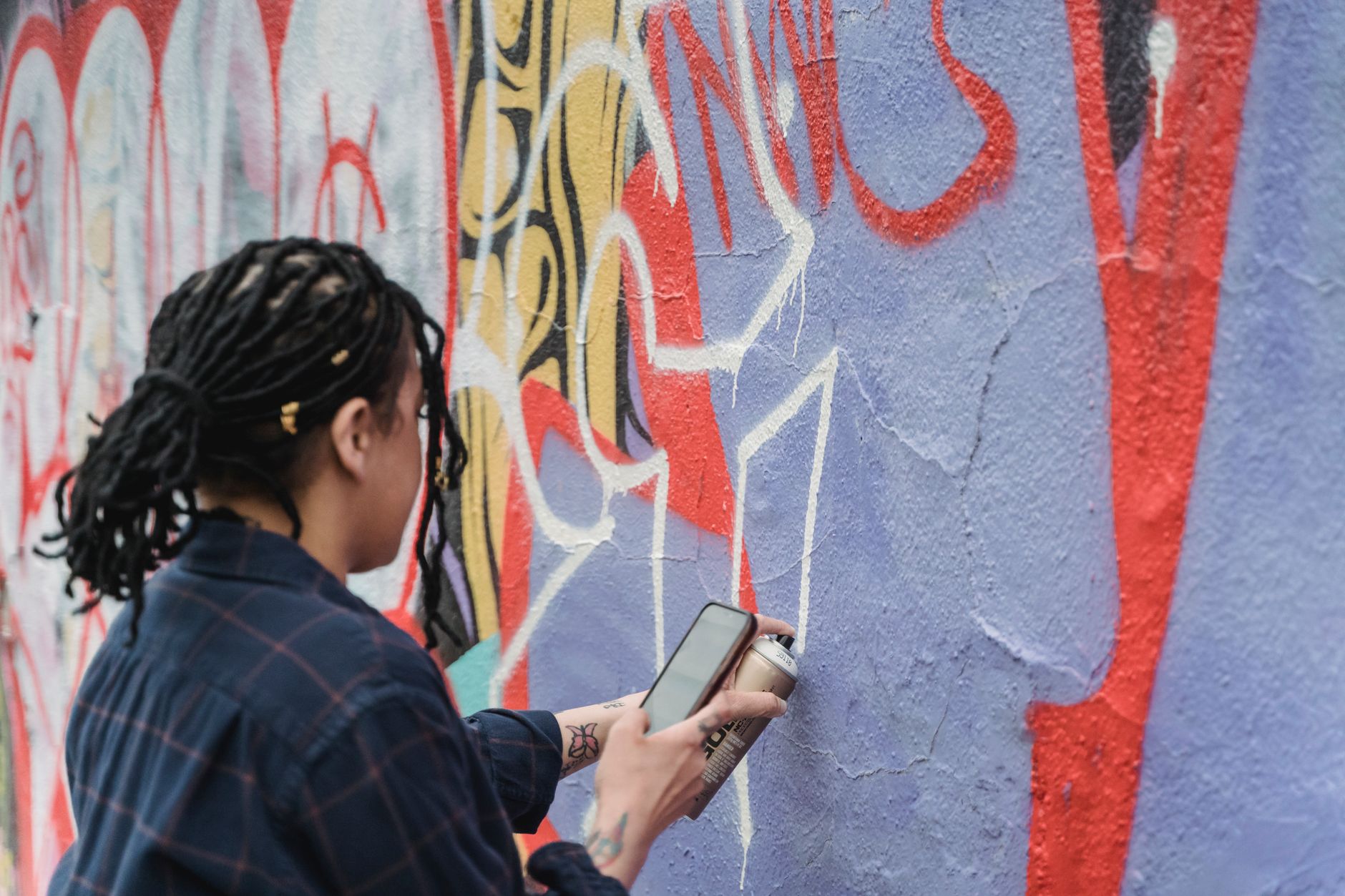 Duvara sprey boyayla grafiti yapan bir sanatçının elleri