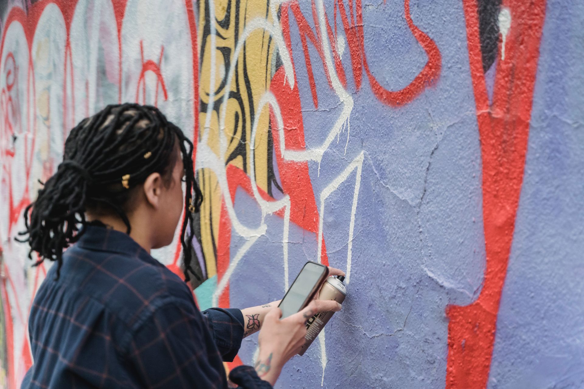 A person painting vibrant graffiti on a wall using spray paint outdoors.