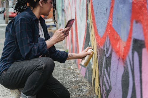 Free A Woman Doing Graffiti on the Wall Stock Photo