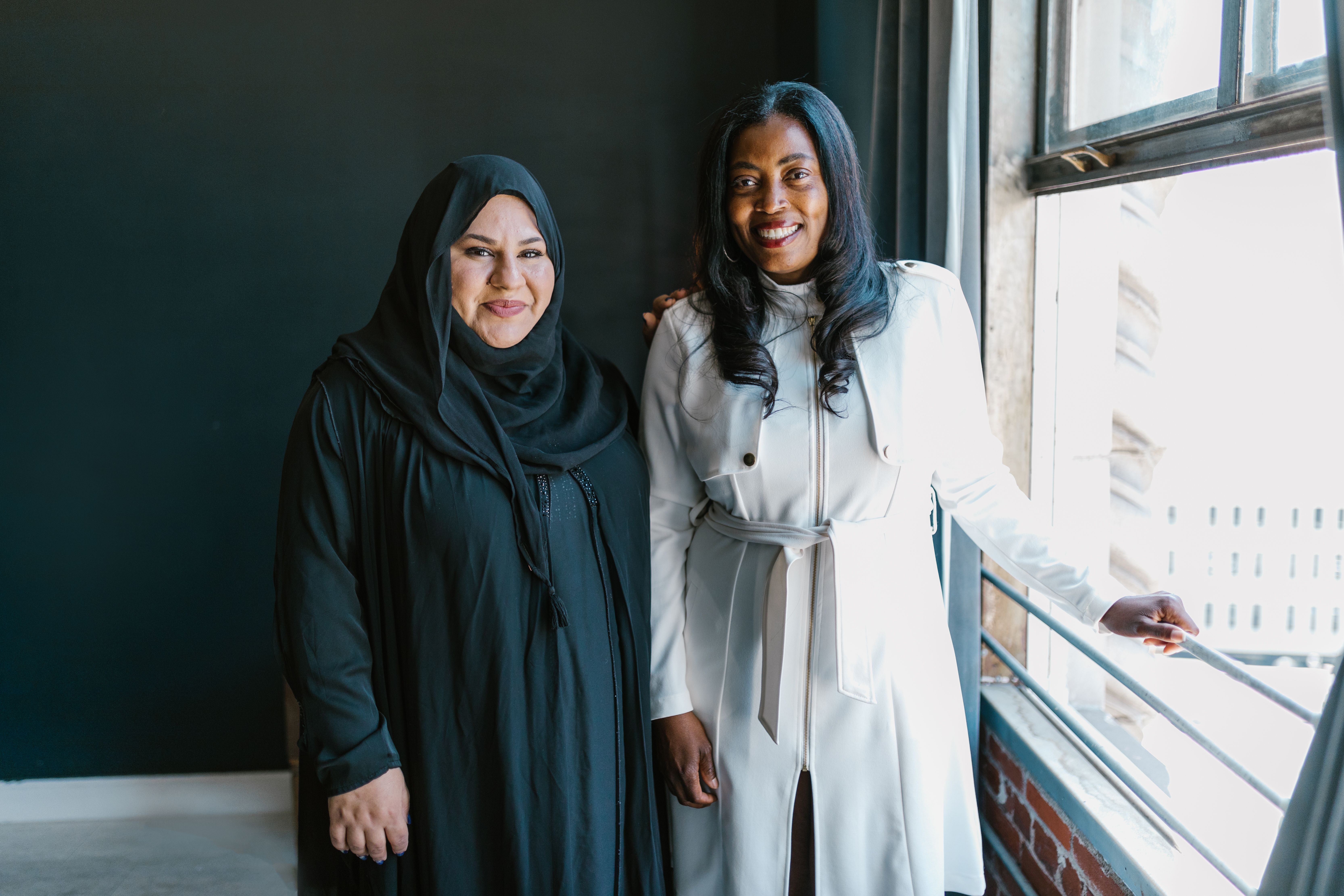 Portrait of Smiling Women Standing by Window · Free Stock Photo