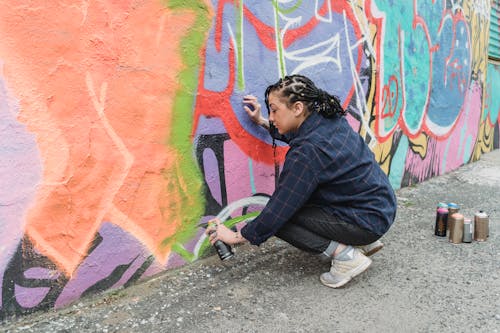 A Woman Doing Graffiti on a Wall Using a Spray Paint