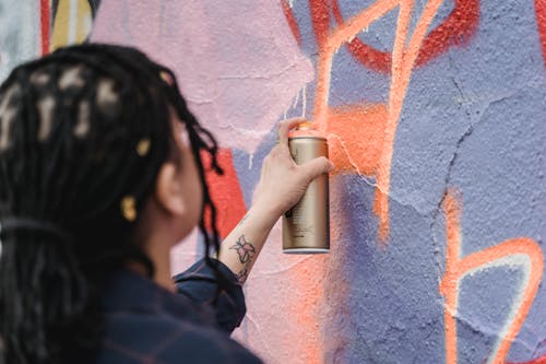 Close-Up Shot of a Woman Doing Graffiti on a Wall Using a Spray Paint