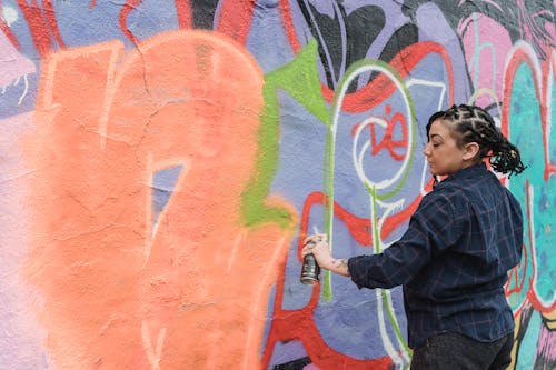A Woman Doing Graffiti on a Wall Using a Spray Paint