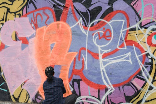 A Woman Doing Graffiti on a Wall Using a Spray Paint