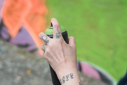 Selective Focus Shot of a Person's Hand Holding a Spray Paint