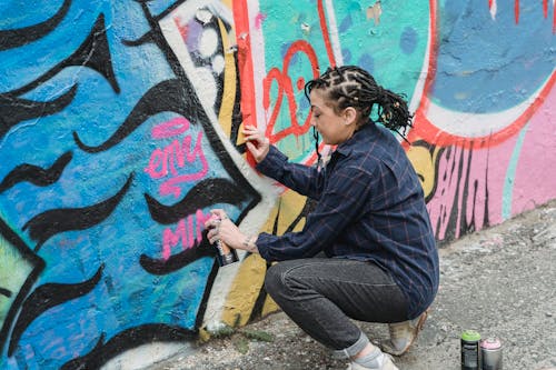 Person Spraying Paint on the Graffiti Wall 