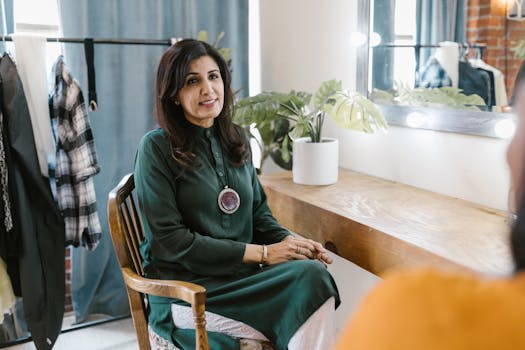 Woman in green dress sitting in cozy dressing room. Stylish and elegant setup for a studio shoot.
