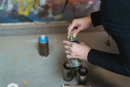 Person Holding the Cap of the Spray Paint 