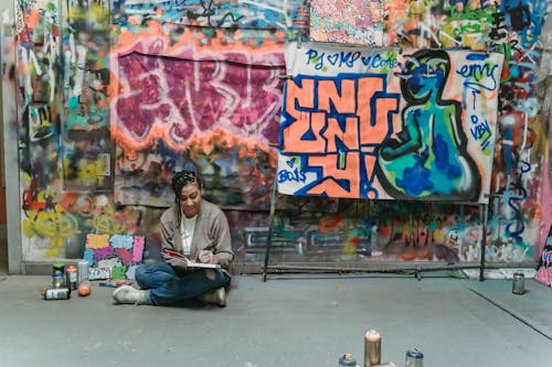 A Woman Sitting on the Floor with Background Graffiti