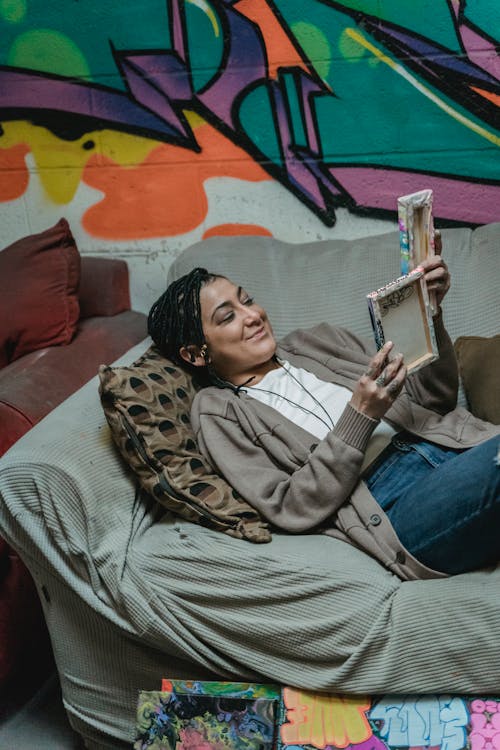 Free Smiling Woman Lying Down on Couch While Looking at Her Artwork Stock Photo