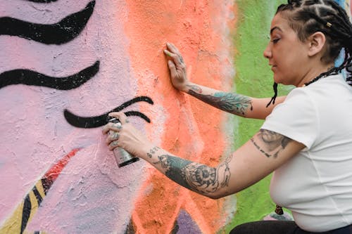 A Woman Doing Graffiti on a Wall Using a Spray Paint