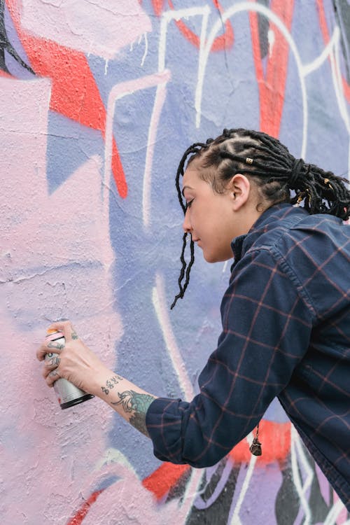 A Woman Doing Graffiti on a Wall Using a Spray Paint