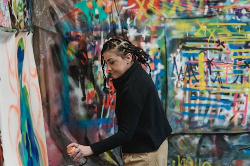 A Woman Doing Graffiti on a Wall Using a Spray Paint