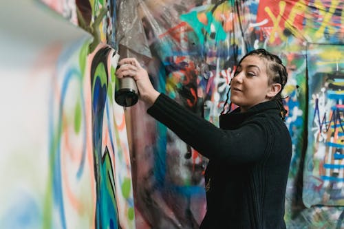 A Woman Doing Graffiti on a Wall Using a Spray Paint