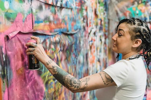 A Woman Doing Graffiti on a Wall Using a Spray Paint