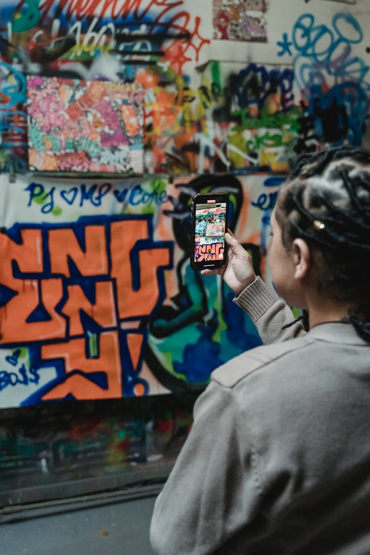 Woman Taking Photo Of Graffiti On Mobile