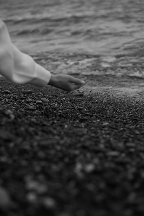 Grayscale Photo of a Person Holding Beach Sand