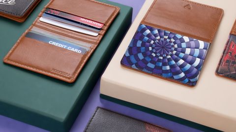 Close-up of assorted leather wallets and cardholders on a modern violet and green background.