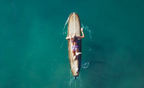 Free Female surfer floating on surfboard in sea Stock Photo