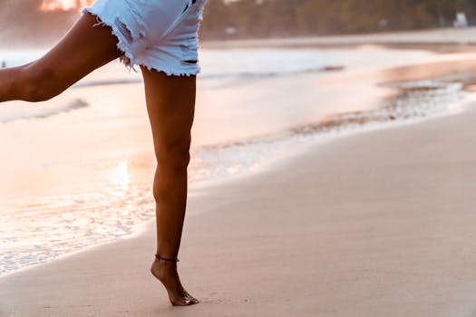 A woman enjoying a tranquil stroll on a sandy beach at sunset, embracing freedom and leisure.