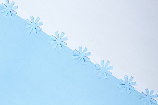 Minimalist design of paper snowflakes on a blue and white background, perfect for winter decor.