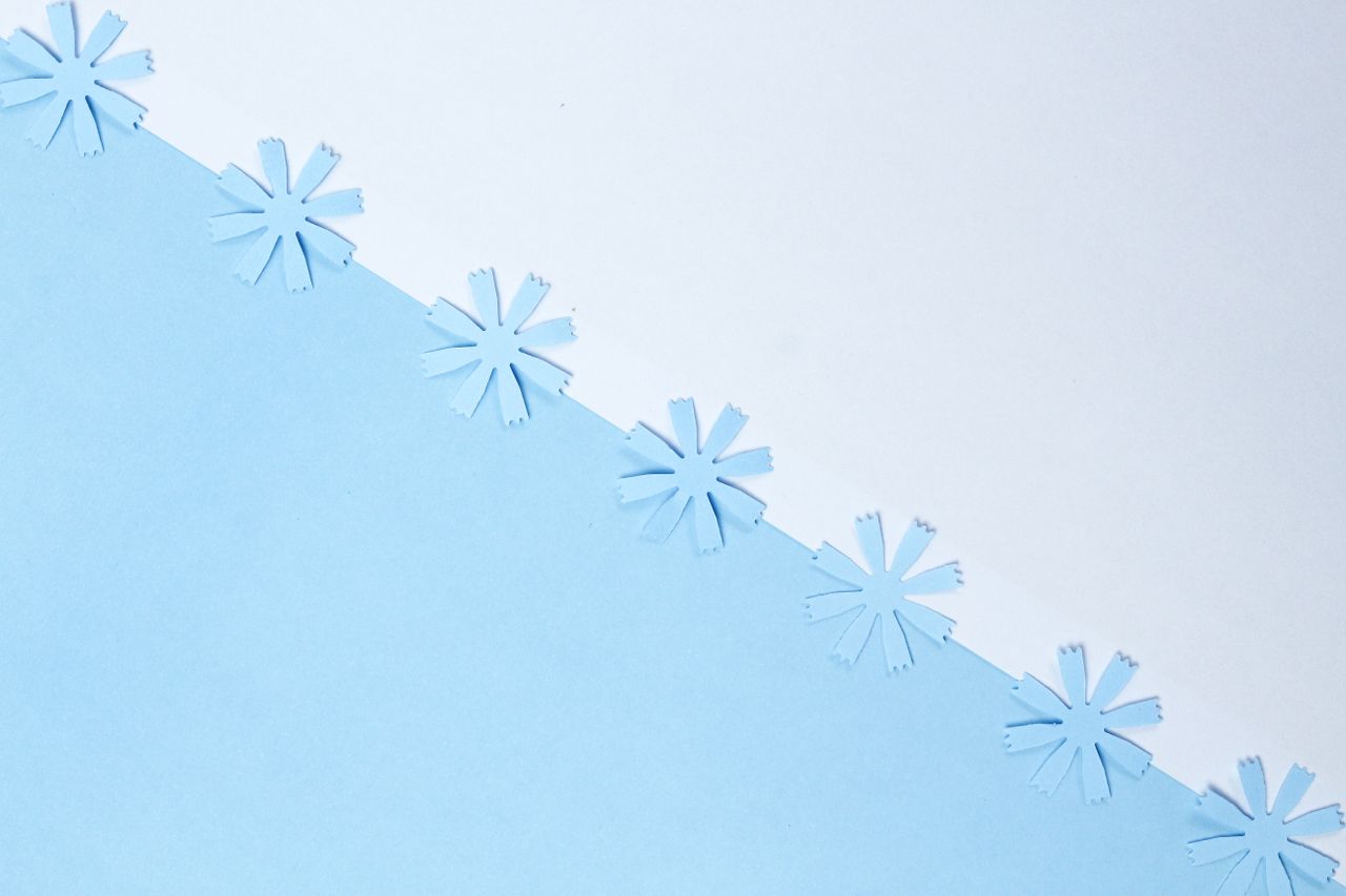 minimalist design of paper snowflakes on a blue and white background p
