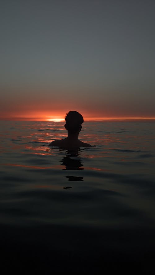 Free Silhouette of Man Bathing in the Sea at Sunset Stock Photo