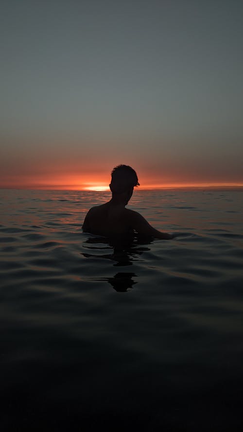 Silhouette of a Man in the Sea at Sunset