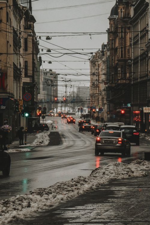 Free Traffic navigates a snow-covered street in Riga, Latvia, on a gloomy winter day. Stock Photo